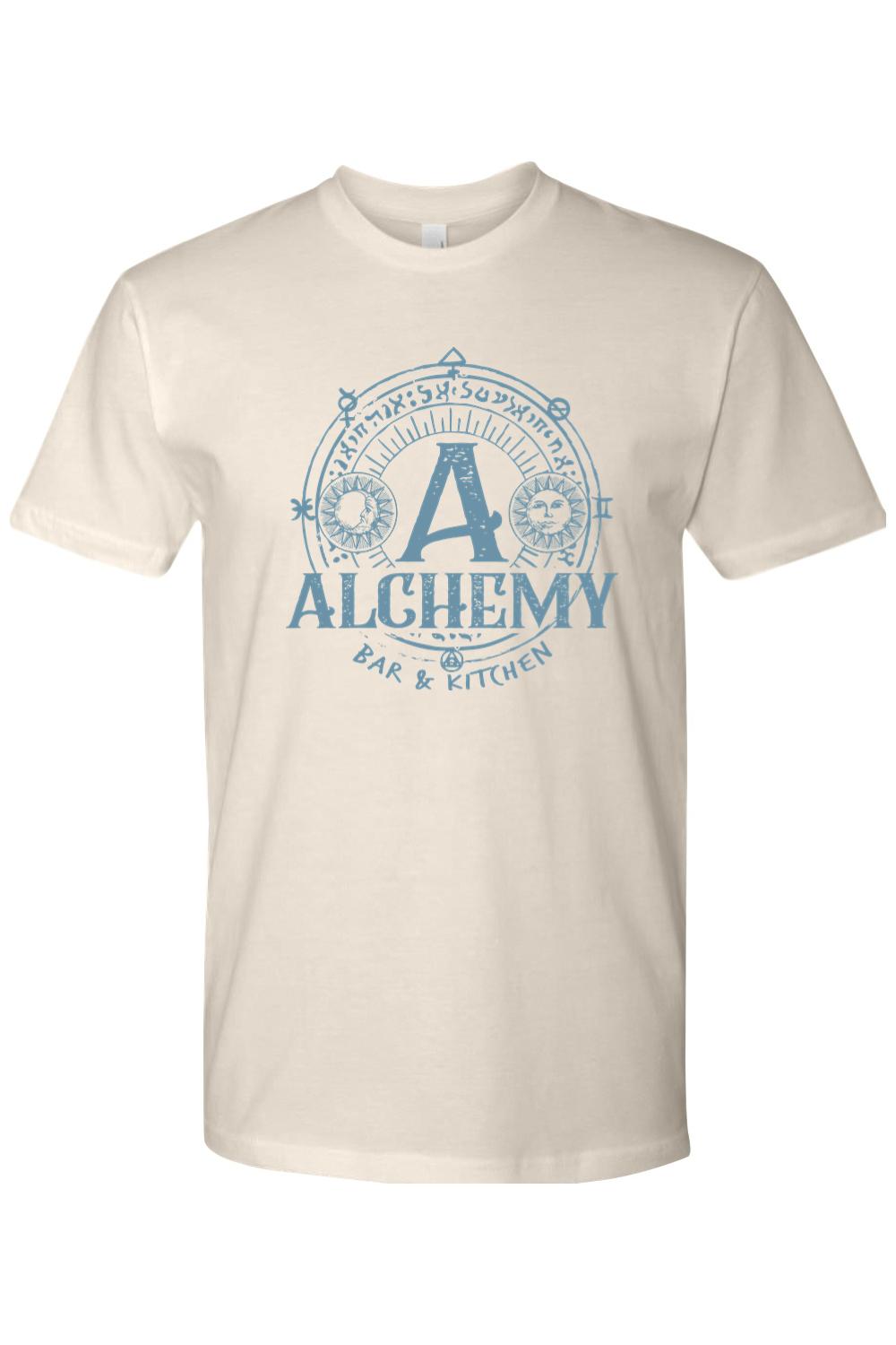 Cream-colored unisex t-shirt featuring a blue Alchemy Bar & Kitchen logo with celestial sun and moon graphic elements.