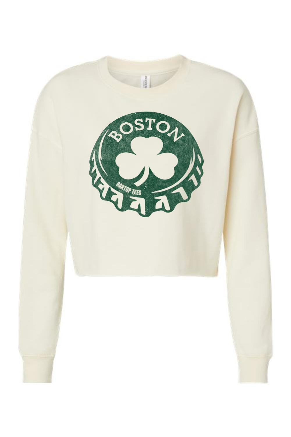 Cream-colored women's crop sweatshirt featuring a green Boston bottle cap graphic with a shamrock design.