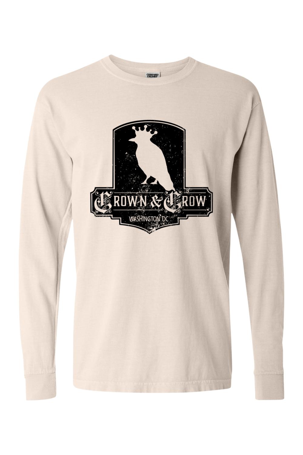 Beige garment-dyed long sleeve t-shirt featuring a black distressed Crown & Crow logo graphic on the chest.