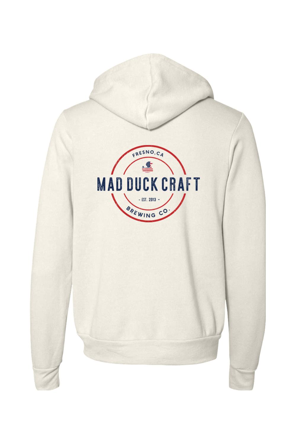 Cream-colored full-zip sponge fleece hoodie featuring a red, white, and blue Mad Duck Craft Brewing Co. logo on the back.