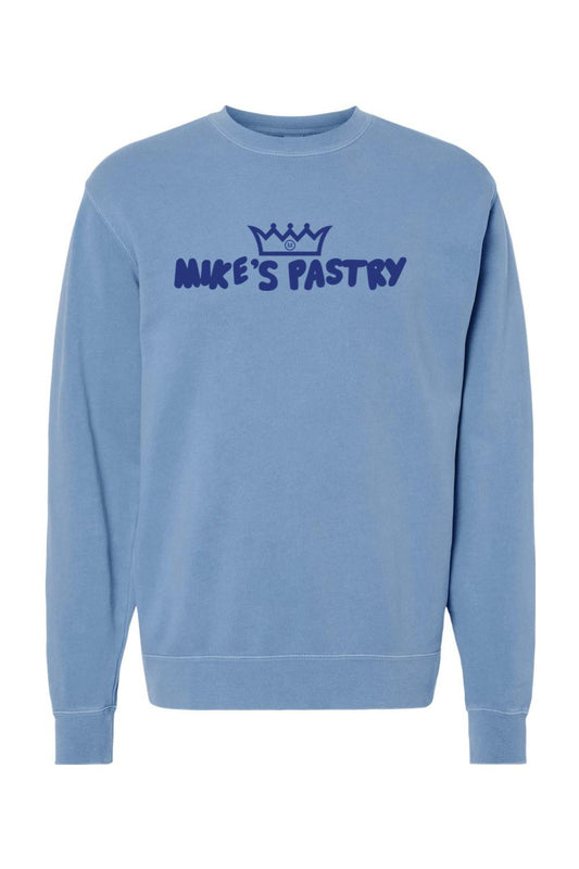 Blue pigment-dyed crewneck sweatshirt with a dark blue Mike's Pastry logo and crown graphic on the chest.