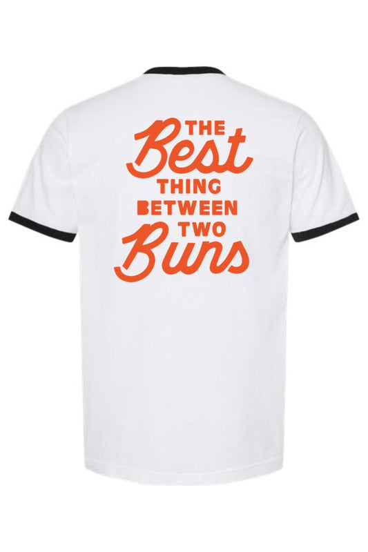 White cotton ringer tee with black trim and orange text reading The Best Thing Between Two Buns on the back.