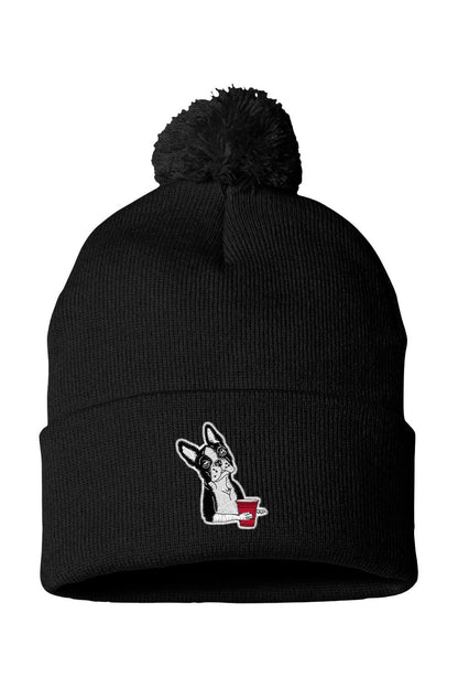 Black knit beanie with a pom-pom, featuring an embroidered Boston terrier holding a red party cup.