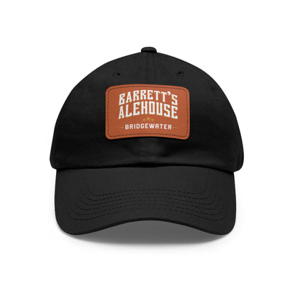 Black bio-washed chino twill dad cap featuring a brown faux leather patch with the Barrett's Alehouse Bridgewater logo.