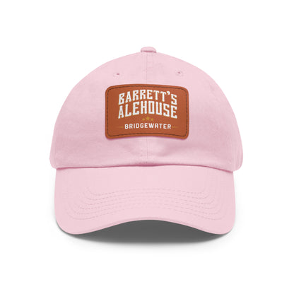 Light pink bio-washed chino twill dad cap with a brown faux leather patch featuring the Barrett's Alehouse logo.