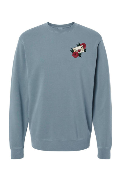Blue pigment-dyed crewneck sweatshirt featuring a small embroidered rose and envelope design on the chest.