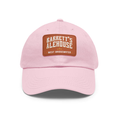 Light pink unstructured dad hat with a brown faux leather patch featuring the Barrett's Alehouse logo.