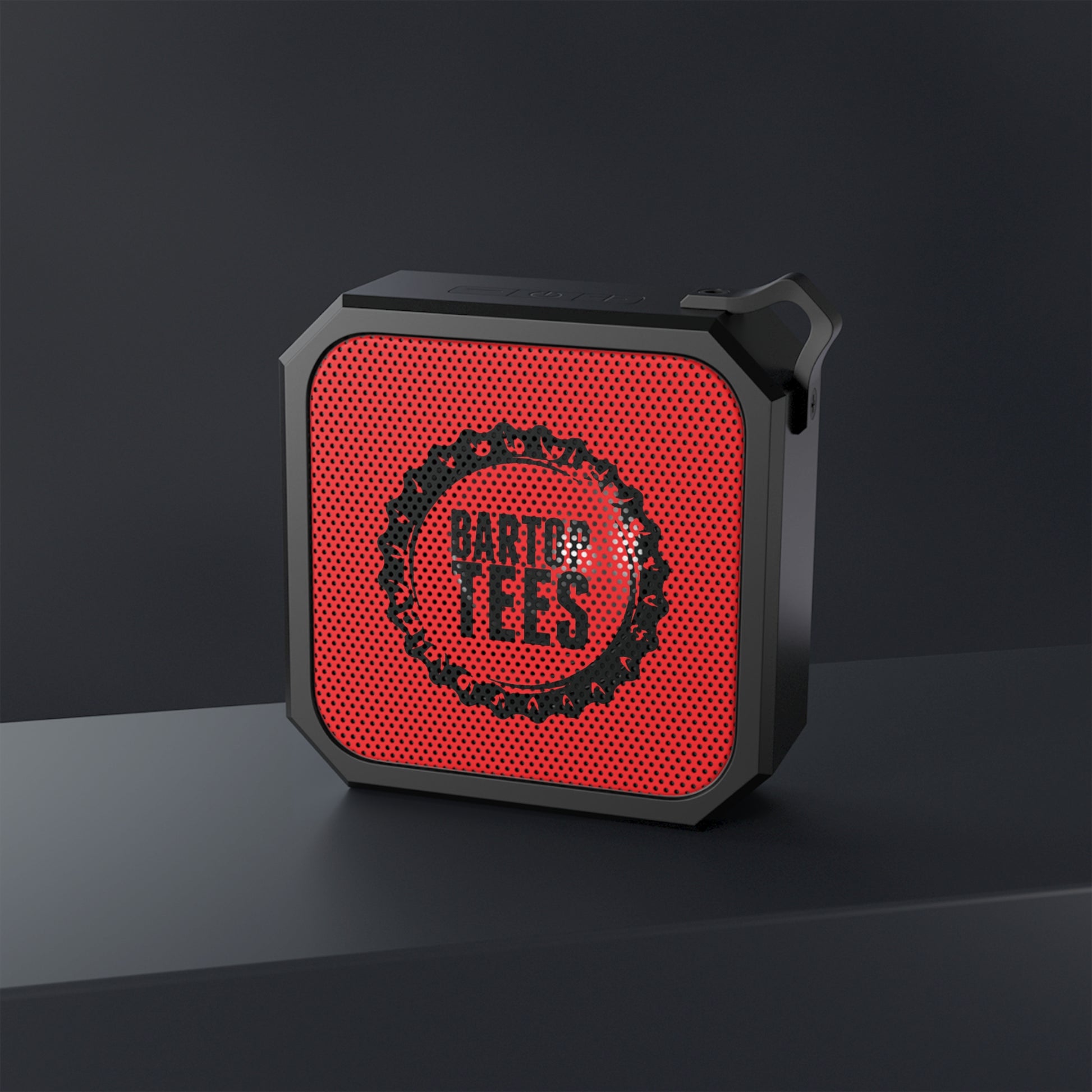 Compact black and red square outdoor Bluetooth speaker with a built-in carabiner clip and mesh grille design.