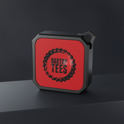 Compact black and red square outdoor Bluetooth speaker with a built-in carabiner clip and mesh grille design.