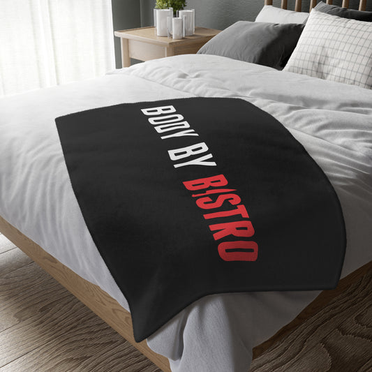 Soft black velveteen minky blanket with Body by Bistro text in white and red, draped over a bed.