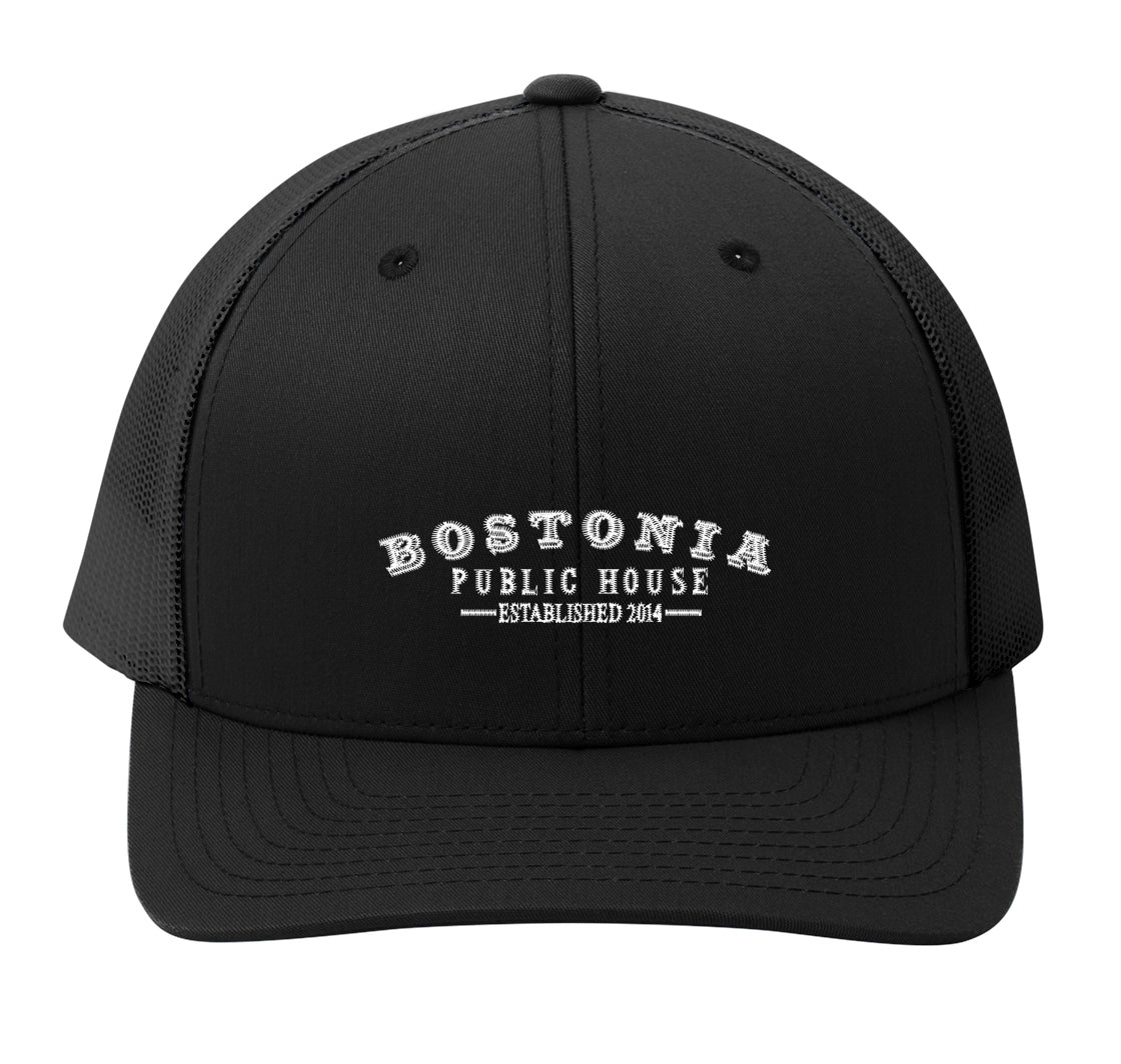 Black Bostonia Public House structured trucker cap with breathable mesh back and adjustable snap closure.
