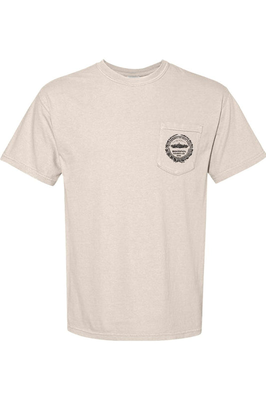 Beige Comfort Colors pocket t-shirt featuring a black Bostonia crest logo on the front chest pocket.