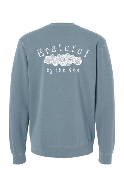 Blue pigment-dyed crewneck sweatshirt featuring a white Grateful by the Sea rose graphic on the back.