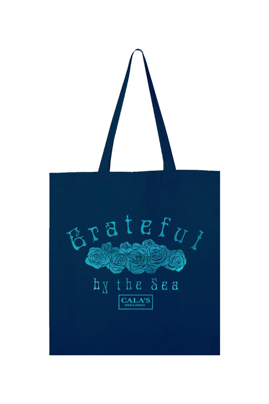 Navy blue canvas tote bag with a teal rose graphic and Grateful By The Sea text with Cala's Food & Spirits logo.