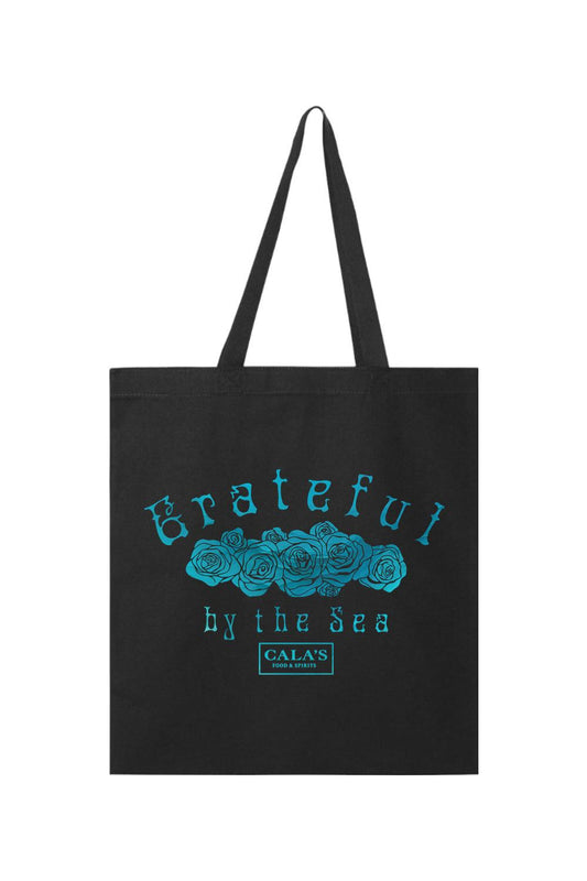 Black canvas tote bag featuring a blue rose graphic with Grateful by the Sea text and Cala's Food & Spirits logo.