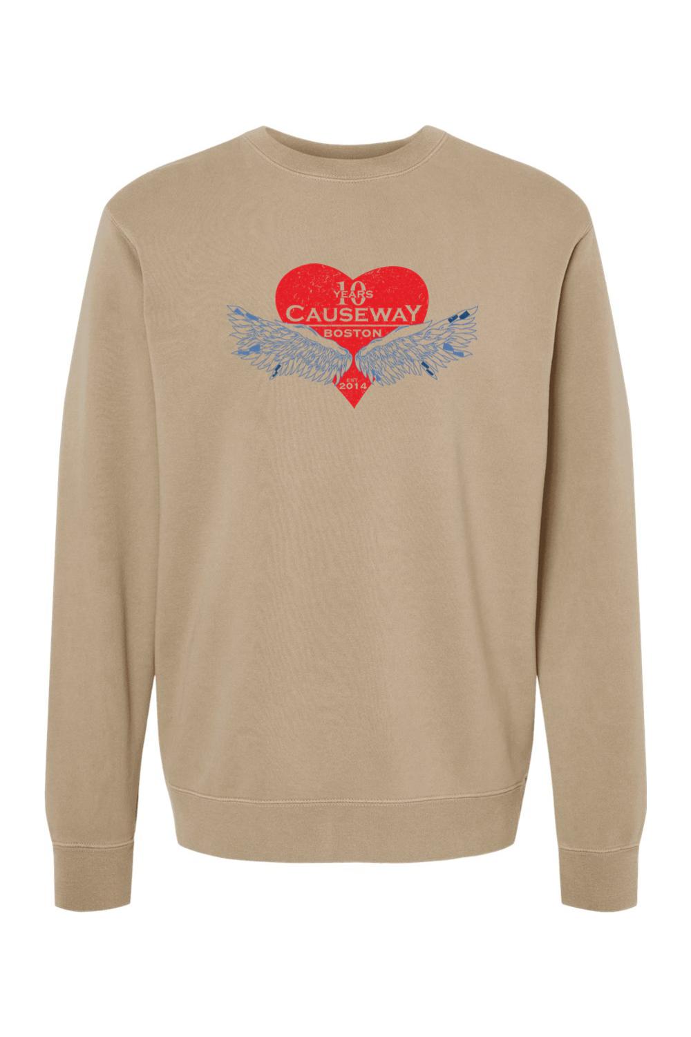 Tan pigment-dyed crewneck sweatshirt featuring a red heart graphic with blue wings and Causeway 10th anniversary text.