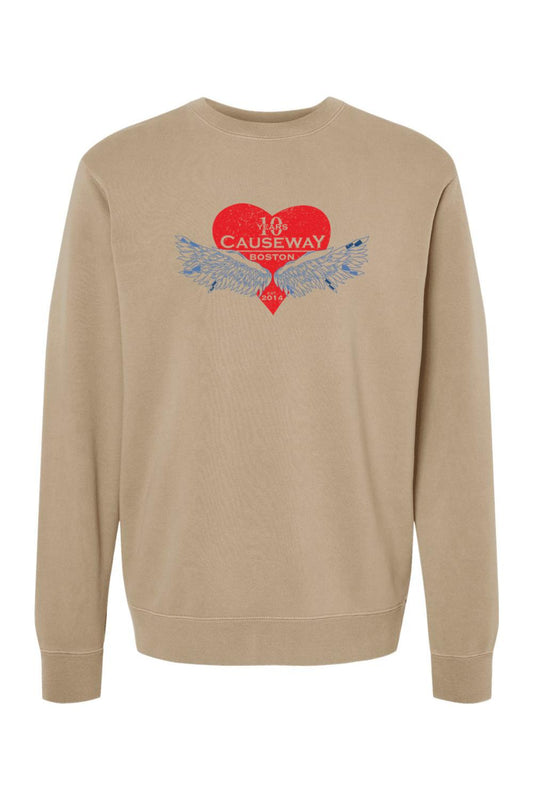 Tan pigment-dyed crewneck sweatshirt featuring a red heart graphic with blue wings and Causeway 10th anniversary text.