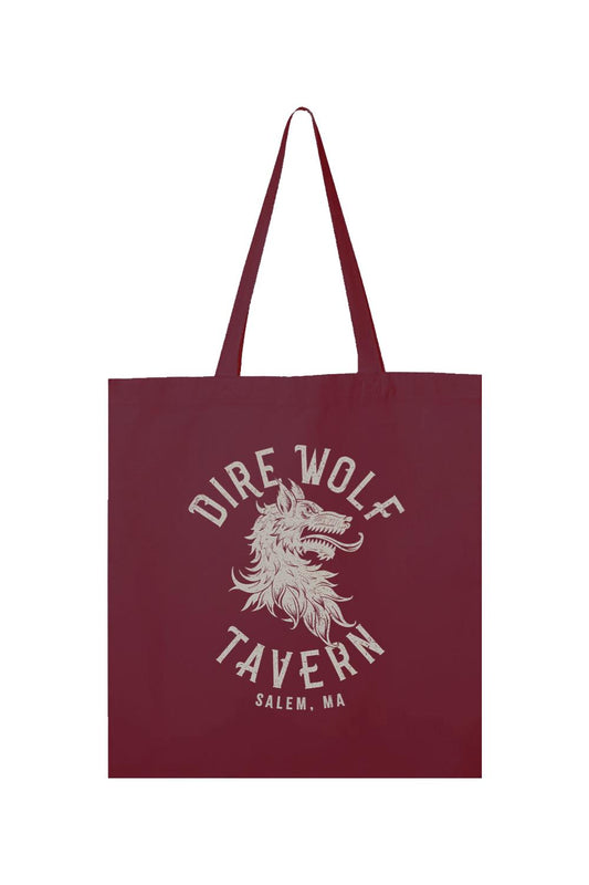 Maroon canvas tote bag featuring a white Dire Wolf Tavern Salem, MA logo graphic and long shoulder straps.