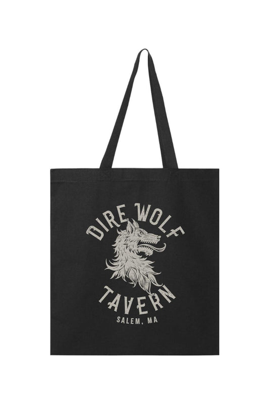 Black canvas tote bag featuring a distressed white Dire Wolf Tavern Salem, MA graphic print and sturdy handles.