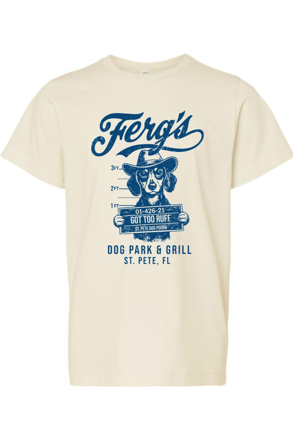 Cream-colored kids' cotton t-shirt featuring a blue graphic of a dog in a cowboy hat holding a mugshot sign.