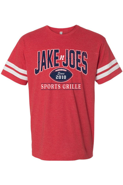 Red cotton football jersey tee with white sleeve stripes and Jake n JOES Sports Grille logo graphic on the chest.