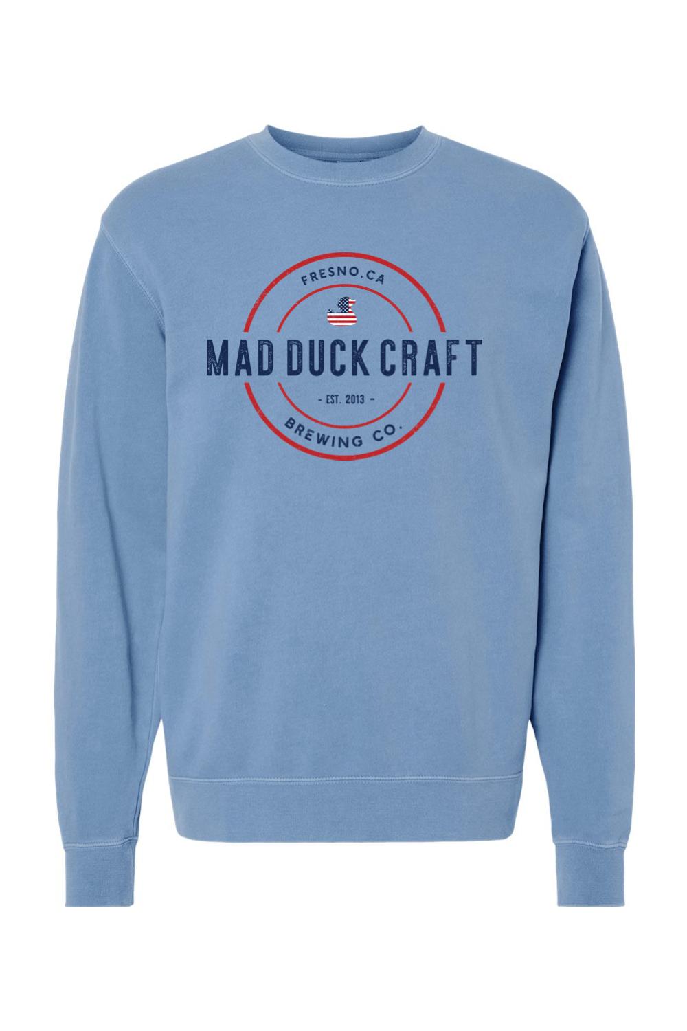 Blue pigment-dyed crewneck sweatshirt featuring a red and blue Mad Duck Craft Brewing Co. logo with a duck icon.