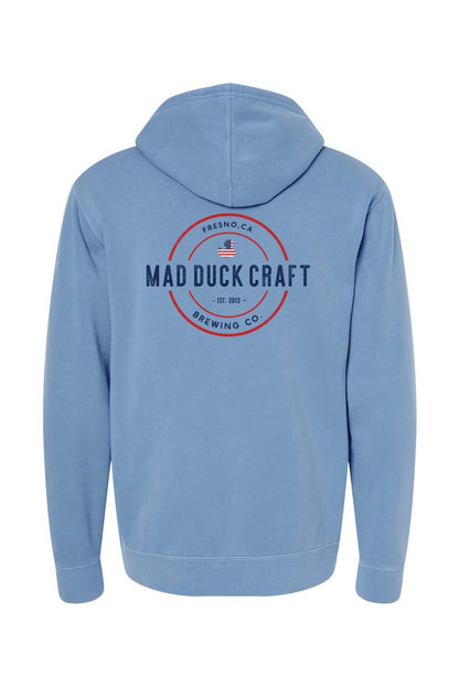 Blue pigment-dyed hoodie featuring a red and blue Mad Duck Craft Brewing Co. logo on the back.