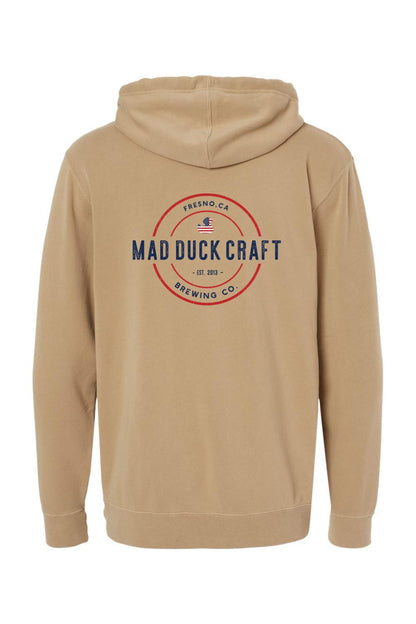 Tan pigment-dyed hoodie featuring a red, white, and blue Mad Duck Craft Brewing Co. logo on the back.