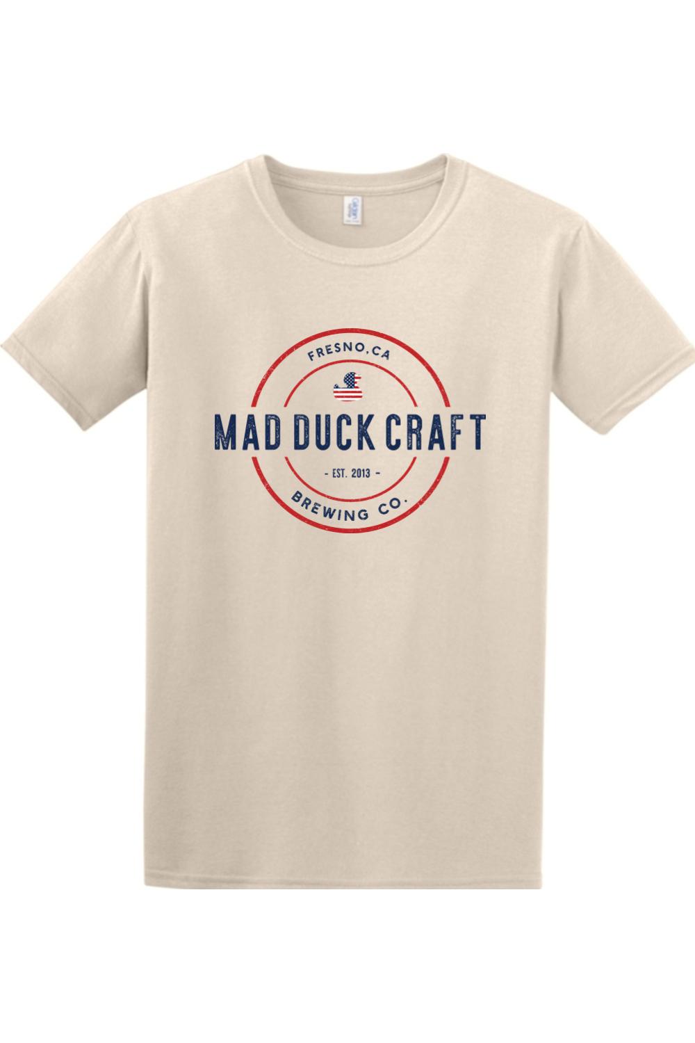 Beige short-sleeve cotton t-shirt featuring a red, white, and blue Mad Duck Craft Brewing Co. logo on the chest.