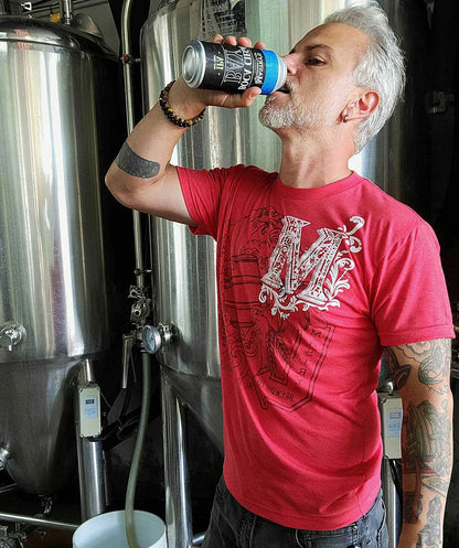 Man wearing a heather red Mastry’s Brewing Co. triblend graphic tee with a white collage logo design.