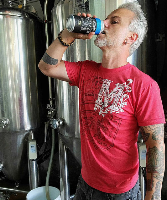 Man wearing a heather red Mastry’s Brewing Co. triblend graphic tee with a white collage logo design.