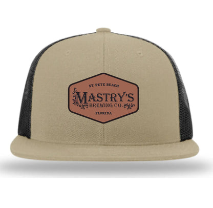 Tan snapback hat with a Mastry’s Brewing Co. leather patch, featuring a structured front and breathable black mesh back.