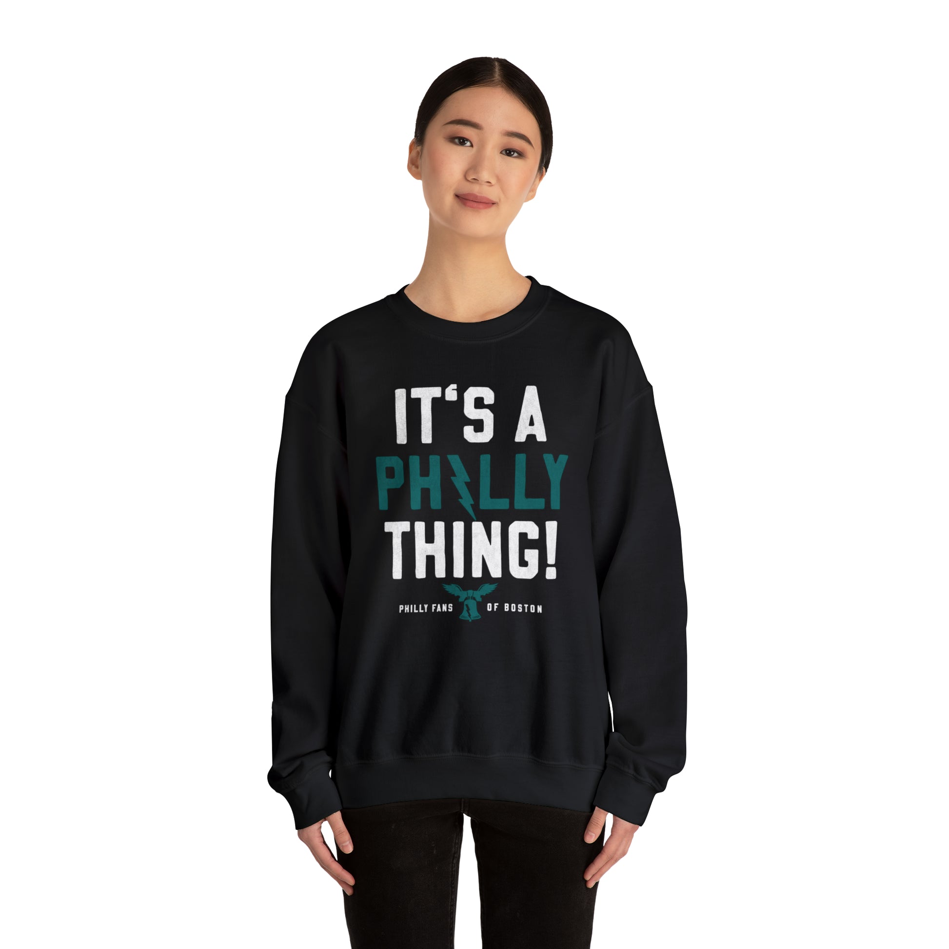 Woman wearing a black unisex heavy blend crewneck sweatshirt with It's a Philly Thing graphic print.
