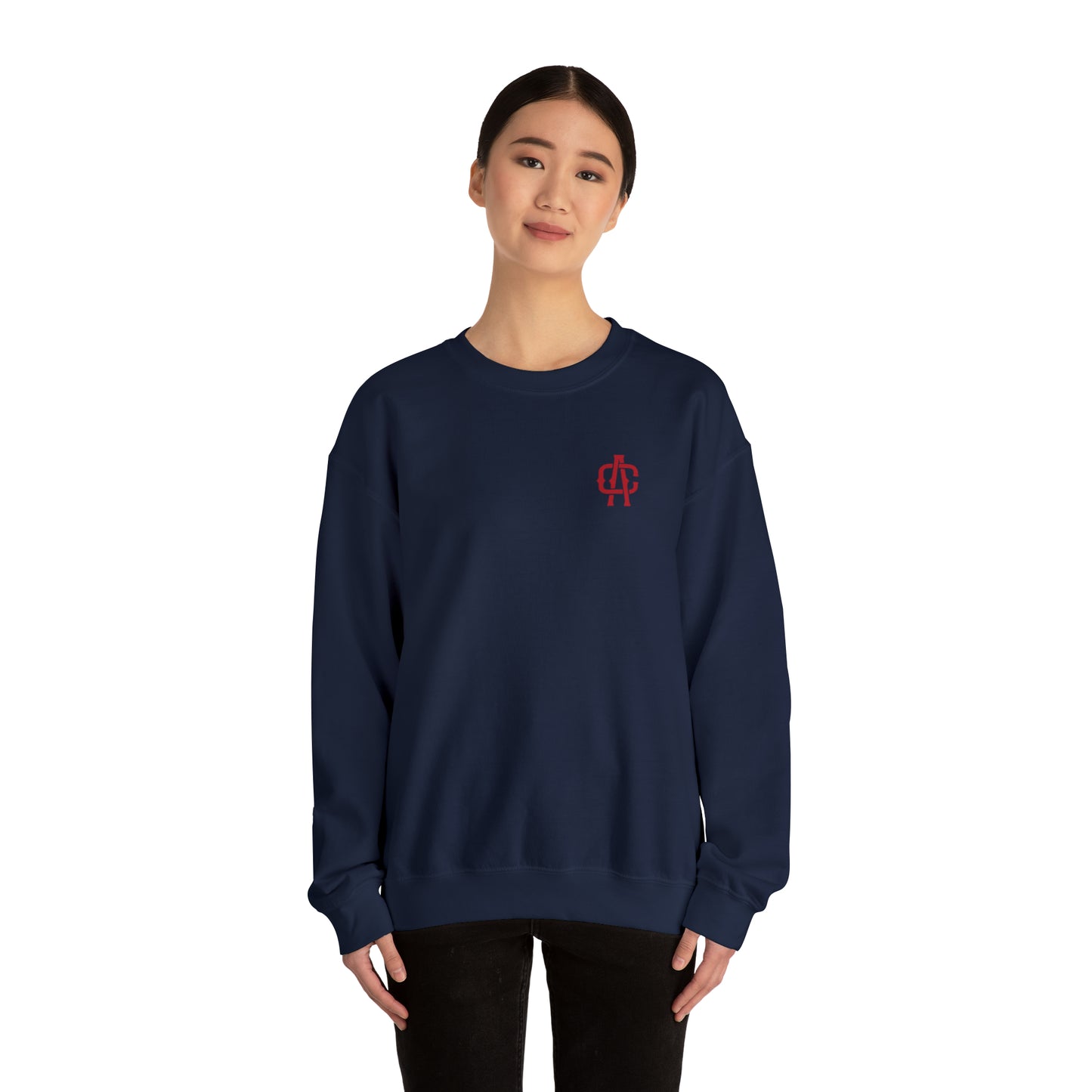 Woman wearing a navy blue heavy blend crewneck sweatshirt with a small red logo on the chest.