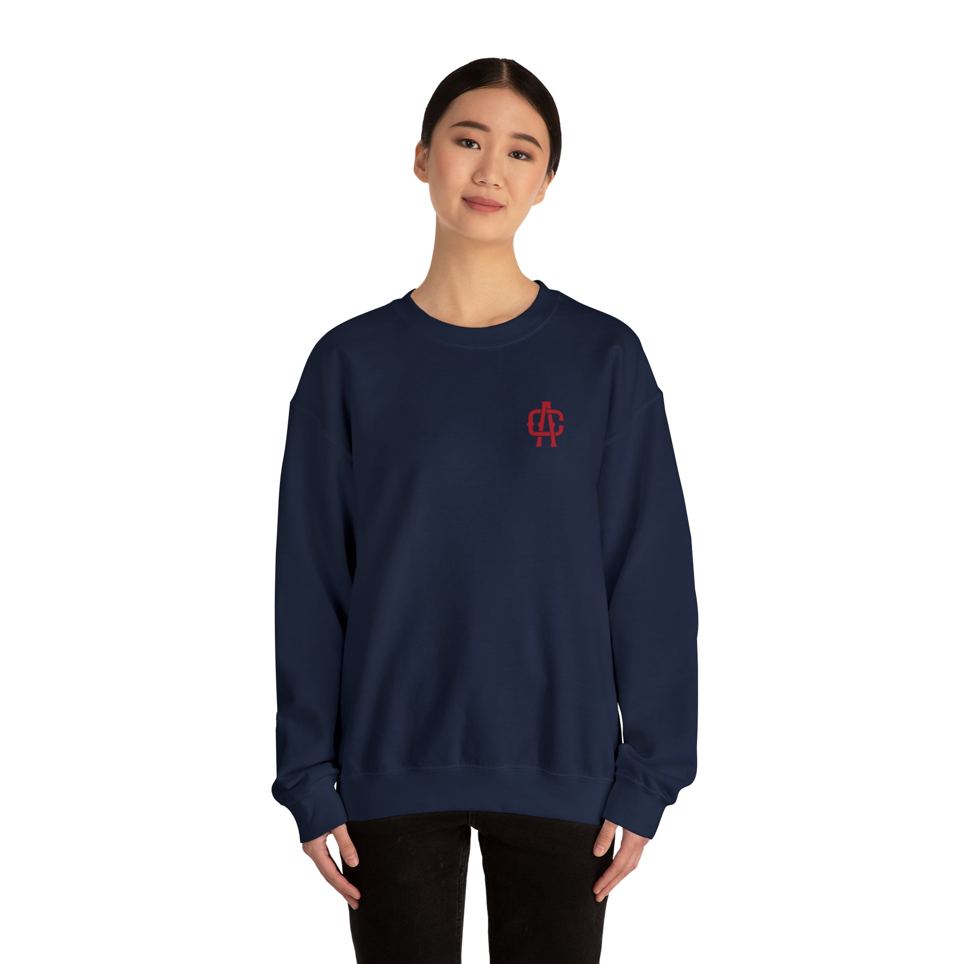 Woman wearing a navy blue heavy blend crewneck sweatshirt with a small red logo on the chest.