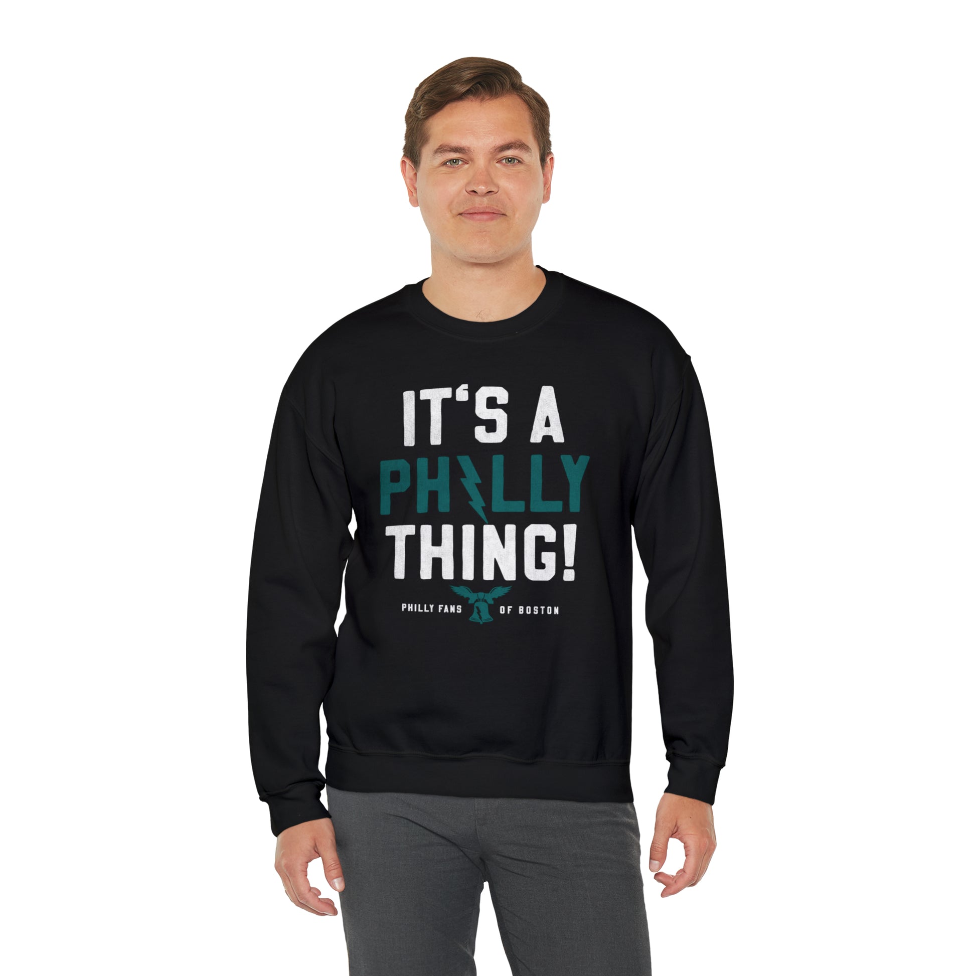 Man wearing a black heavy blend crewneck sweatshirt with It's A Philly Thing graphic print in white and teal.