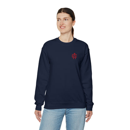Woman wearing a navy blue heavy blend crewneck sweatshirt with a small red embroidered logo on the chest.