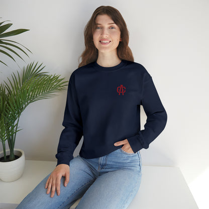 Woman wearing a navy blue heavy blend crewneck sweatshirt with a small red logo on the chest, paired with blue jeans.