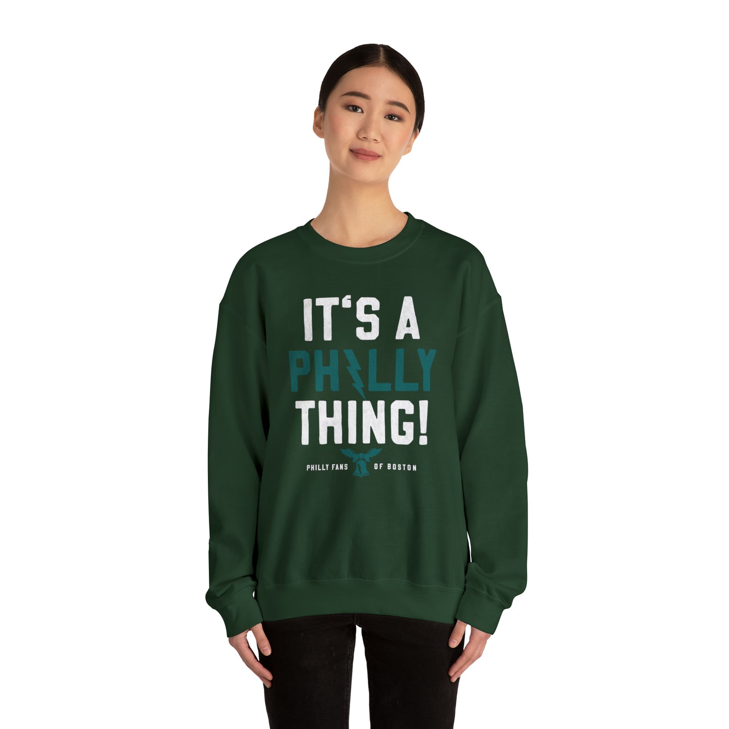 Woman wearing a dark green heavy blend crewneck sweatshirt with white and teal It's a Philly Thing graphic print.