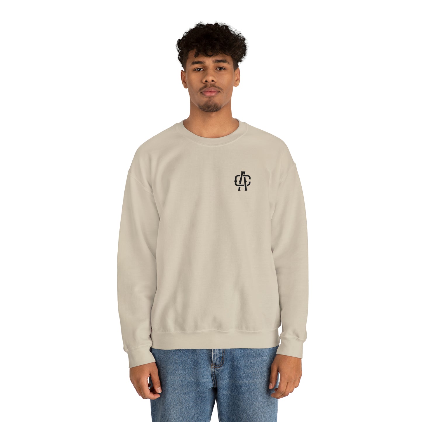 Man wearing a sand-colored heavy blend crewneck sweatshirt with a small black logo on the chest.