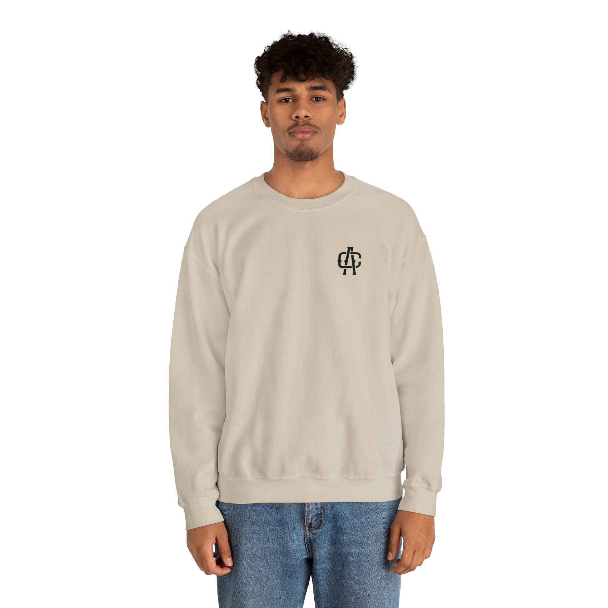 Man wearing a sand-colored heavy blend crewneck sweatshirt with a small black logo on the chest.