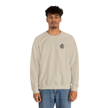 Man wearing a sand-colored heavy blend crewneck sweatshirt with a small black logo on the chest.
