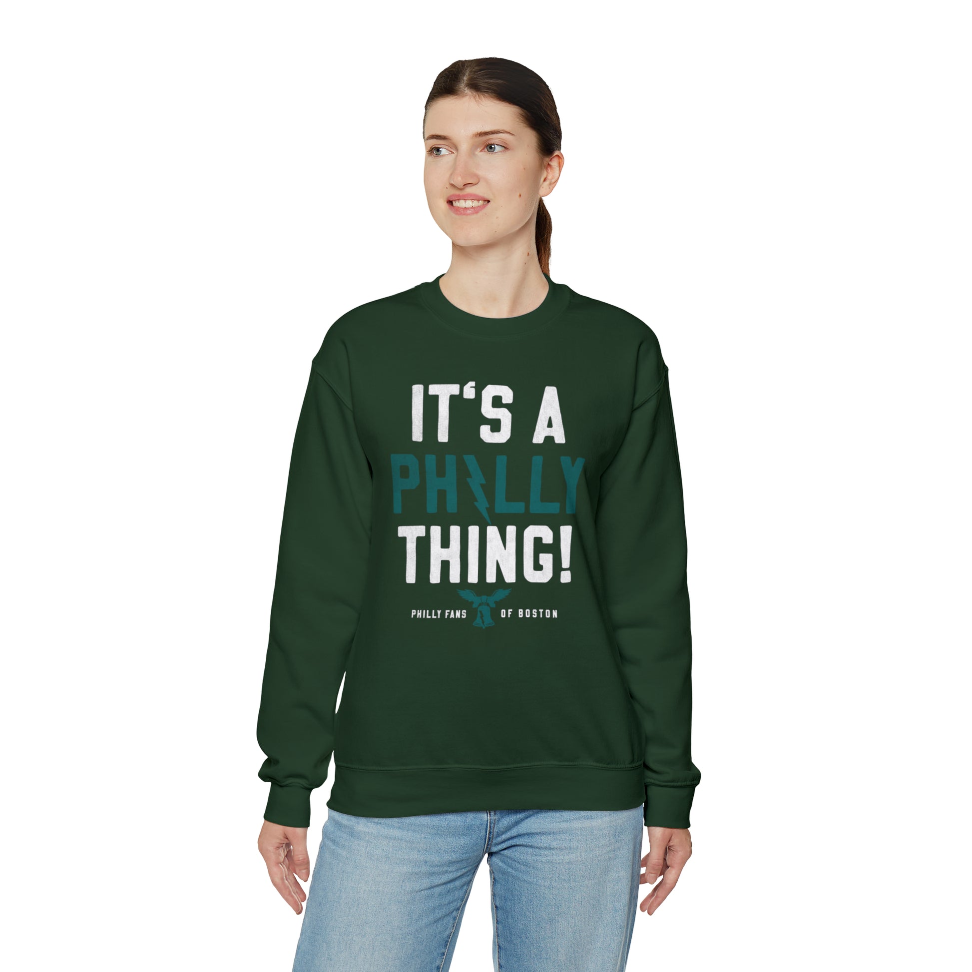 Woman wearing a dark green heavy blend crewneck sweatshirt with It's a Philly Thing graphic print.