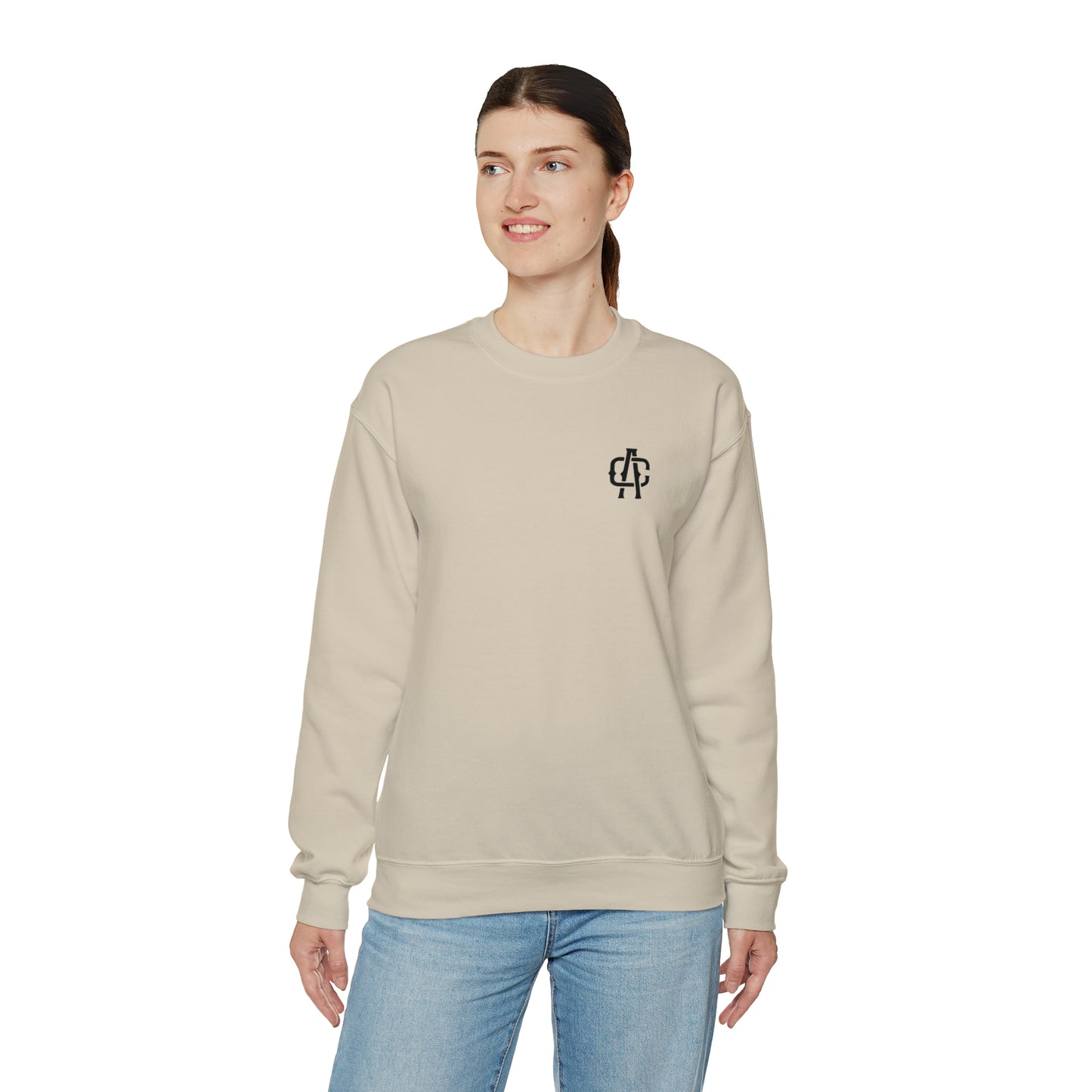 Woman wearing a sand-colored, loose-fit heavy blend crewneck sweatshirt with a small black logo on the chest.