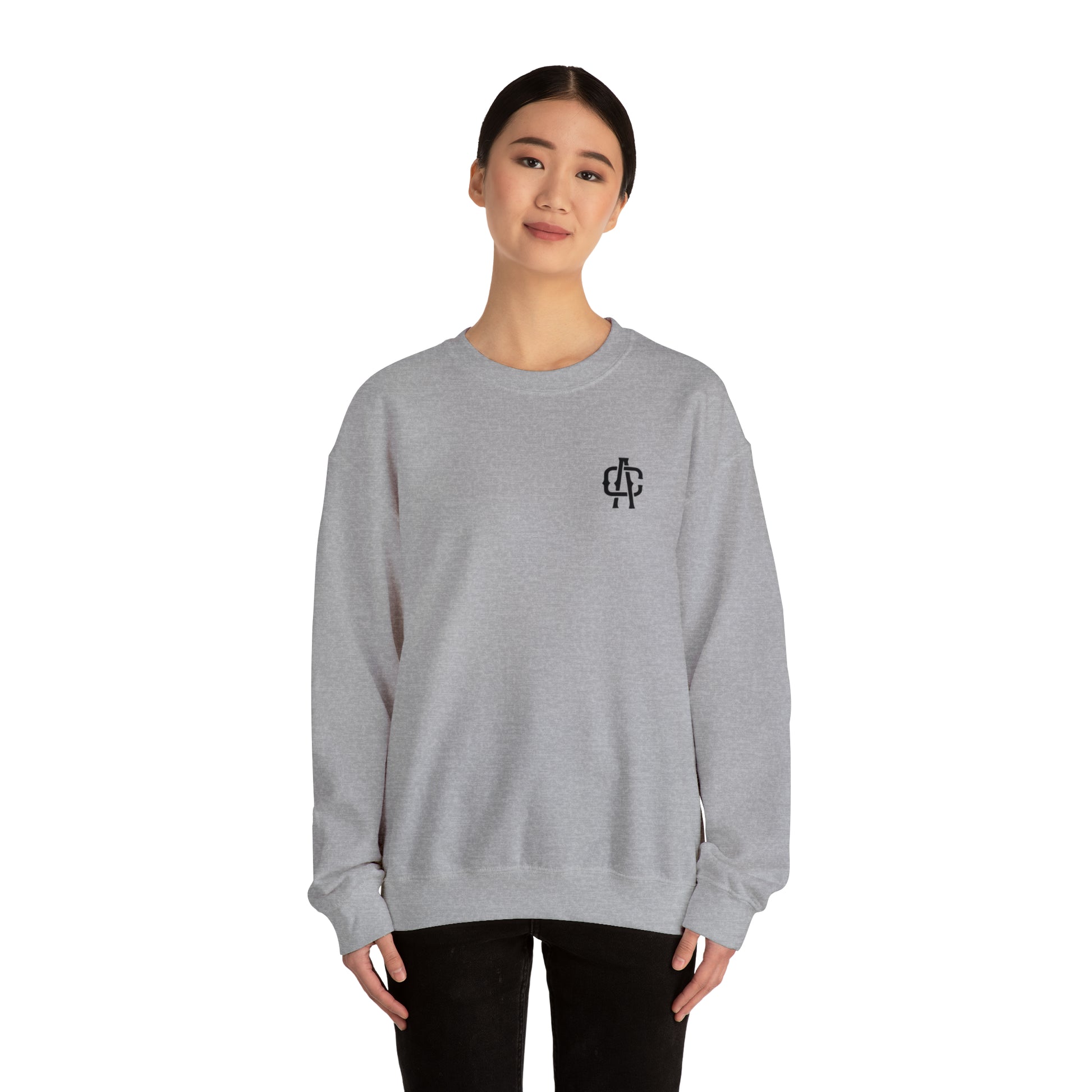 Woman wearing a grey heavy blend crewneck sweatshirt with a small black logo on the chest.