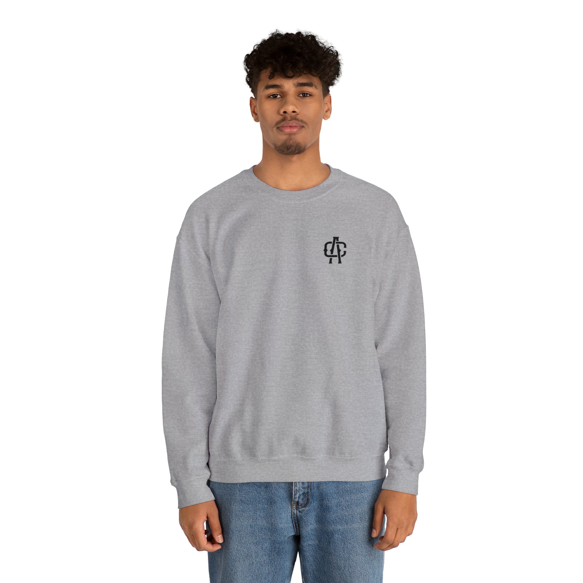 Man wearing a grey, loose-fit heavy blend crewneck sweatshirt with a small black logo on the chest.
