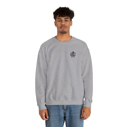 Man wearing a grey, loose-fit heavy blend crewneck sweatshirt with a small black logo on the chest.