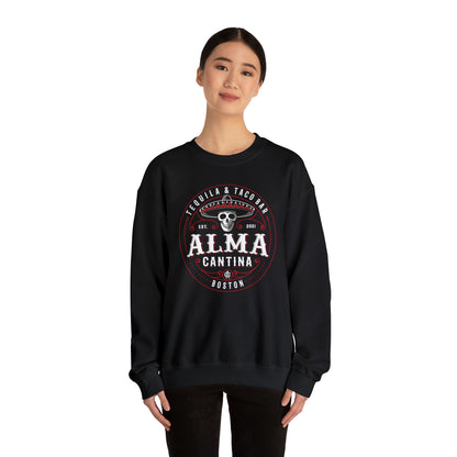 Woman wearing a black crewneck sweatshirt with a white and red Alma Cantina skull logo graphic on the front.