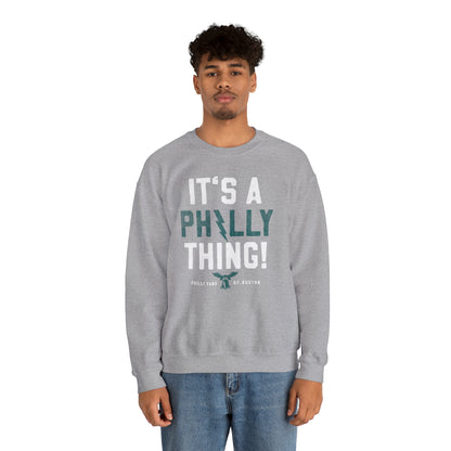Man wearing a grey heavy blend crewneck sweatshirt with It's A Philly Thing text graphic.