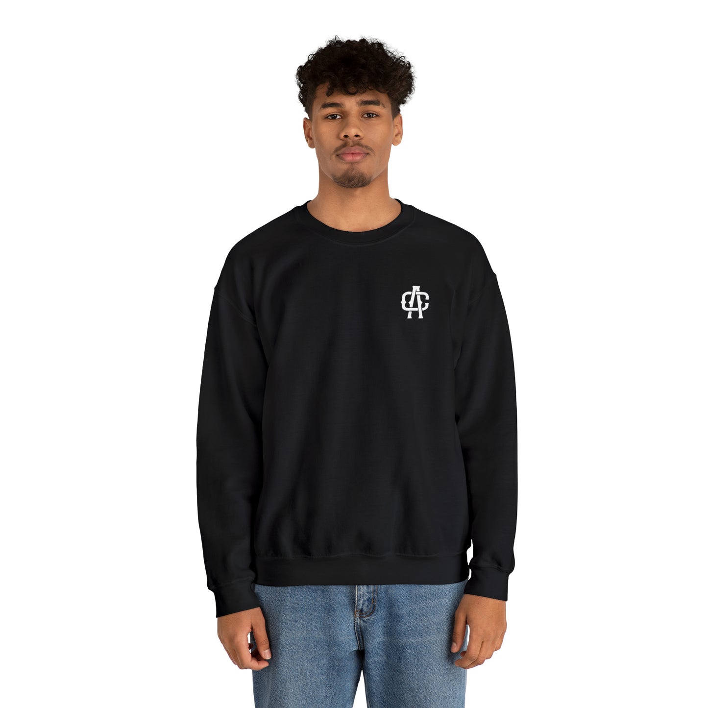 Man wearing a black heavy blend crewneck sweatshirt with a small white logo on the chest and blue jeans.